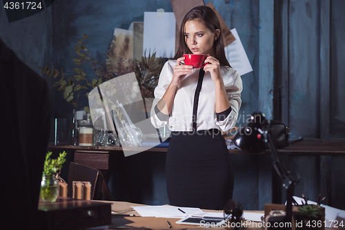 Image of Young beautiful woman working with cup of coffee