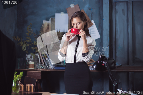 Image of Young beautiful woman working with cup of coffee