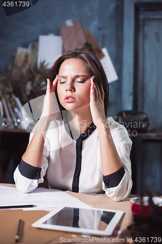 Image of Young frustrated woman working at office desk in front of laptop