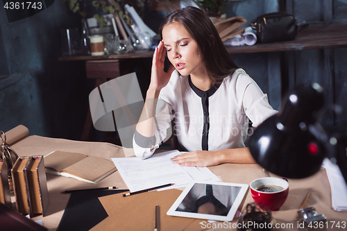 Image of Young frustrated woman working at office desk in front of laptop