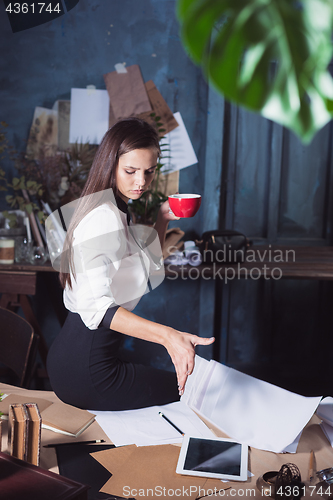 Image of Young beautiful woman working with cup of coffee