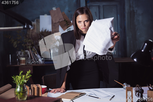 Image of Young business woman throwing documents at camera.