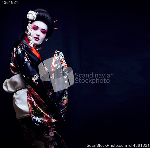 Image of young pretty geisha in kimono with sakura and decoration