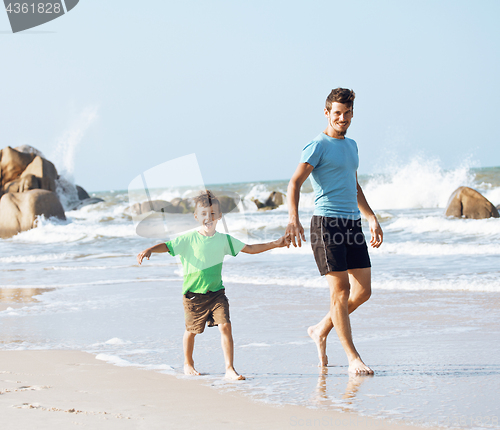 Image of happy family on beach playing, father with son walking sea coast