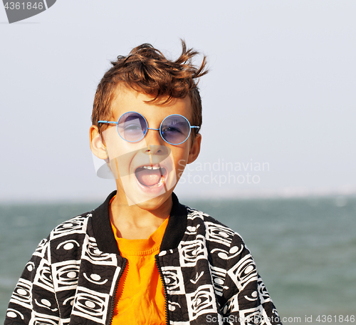 Image of cute little boy at seacoast in fashion clothers and blue glasses