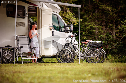 Image of Woman is standing with a mug of coffee near the camper RV.