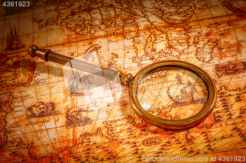 Image of Vintage magnifying glass lies on an ancient world map