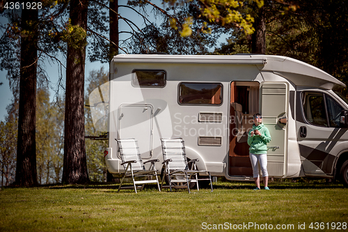 Image of Woman is standing with a mug of coffee near the camper RV.