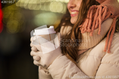 Image of happy woman with coffee over christmas lights