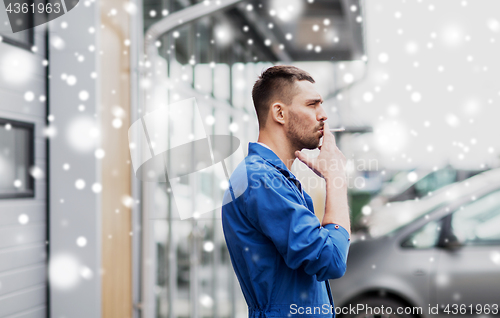 Image of auto mechanic smoking cigarette at car workshop