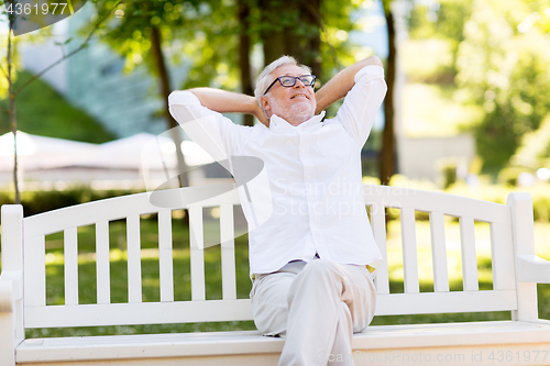 Image of happy senior man sitting on bench at summer park