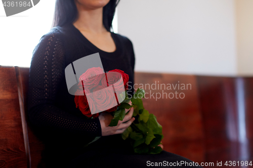 Image of close up of woman with roses at funeral in church