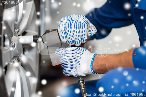 Image of auto mechanic with screwdriver changing car tire