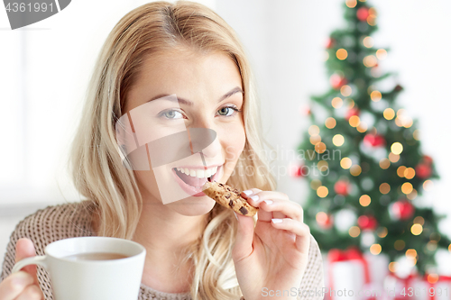 Image of happy woman with coffee eating cookie at christmas
