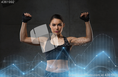 Image of young woman flexing muscles in gym