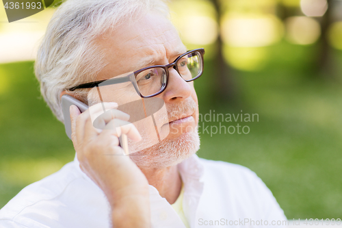 Image of sad senior man in glasses calling on smartphone