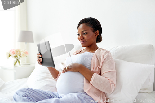 Image of happy pregnant woman with tablet pc at home