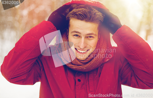 Image of happy man in winter jacket with hood outdoors