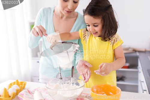 Image of happy mother and daughter baking at home