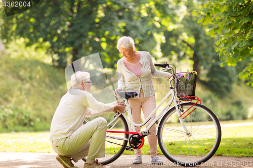 Image of happy senior couple with bicycle at summer park