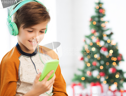 Image of boy with smartphone and headphones at christmas