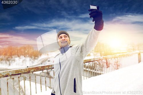 Image of man taking selfie with smartphone in winter 