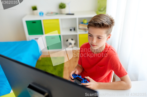 Image of boy with gamepad playing video game on computer