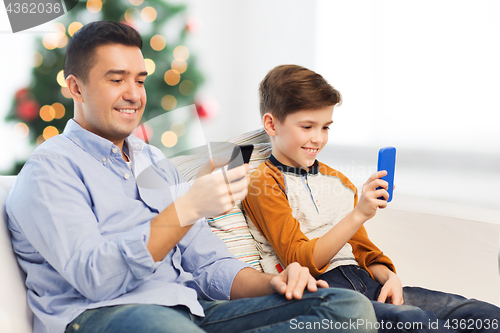 Image of happy father and son with smartphones at christmas