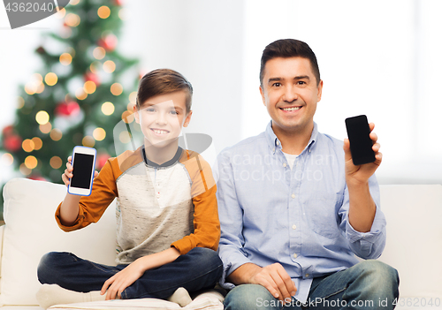 Image of happy father and son with smartphones at christmas