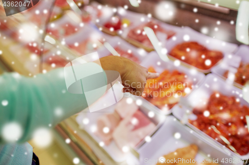 Image of customer hand pointing at meat on grocery stall