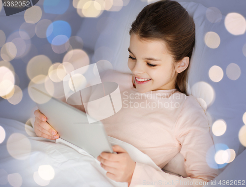 Image of happy girl in bed with tablet pc over lights