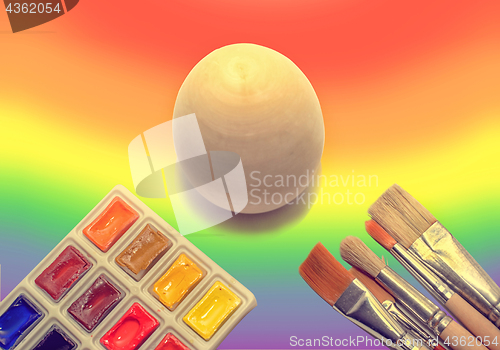 Image of Wooden not painted egg on the background of a rainbow and a brus