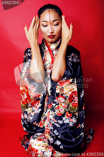 Image of young pretty geisha on red background posing in kimono, oriental people concept 