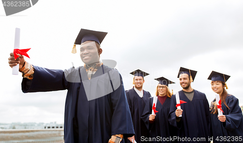 Image of happy students in mortar boards with diplomas