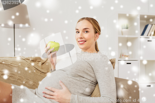 Image of happy pregnant woman with green apple