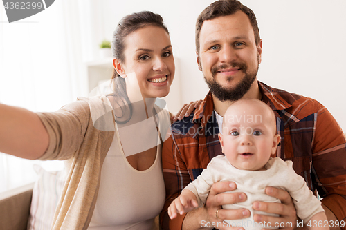 Image of mother and father with baby taking selfie at home