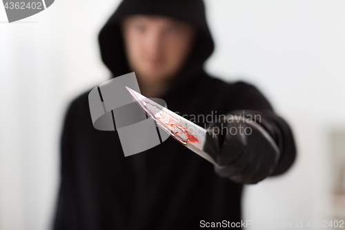 Image of close up of criminal with blood on knife