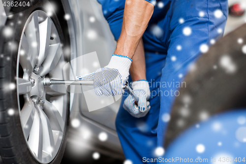 Image of auto mechanic with screwdriver changing car tire