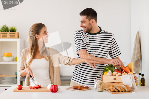 Image of happy couple cooking food at home kitchen