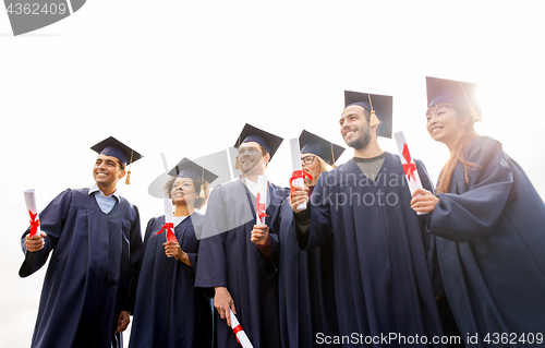 Image of happy students in mortar boards with diplomas