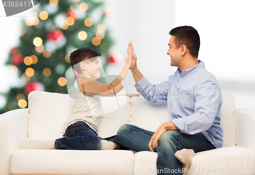 Image of happy father and son doing high five at christmas