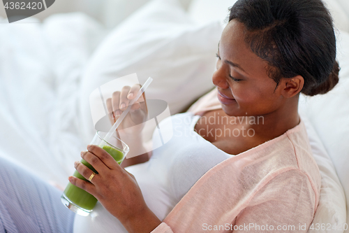 Image of pregnant woman drinking vegetable juice in bed