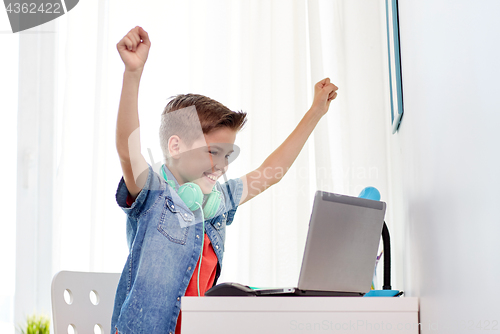 Image of boy with headphones playing video game on laptop