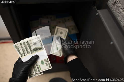 Image of thief stealing money from safe at crime scene