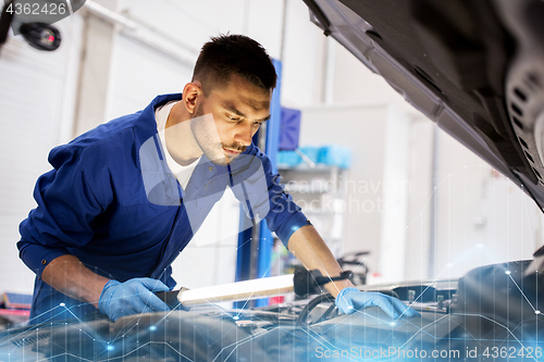 Image of mechanic man with lamp repairing car at workshop