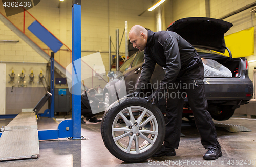 Image of auto mechanic changing car tire at workshop