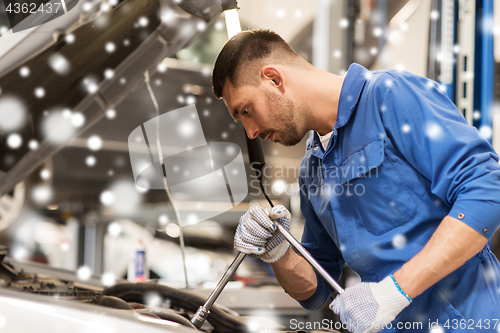 Image of mechanic man with wrench repairing car at workshop