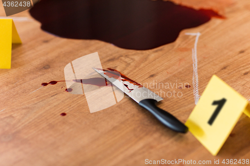 Image of knife in blood and chalk outline at crime scene