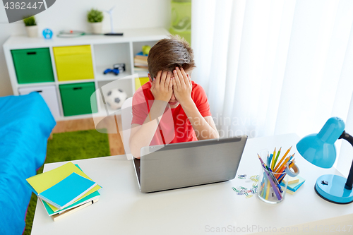 Image of upset student boy with laptop computer at home