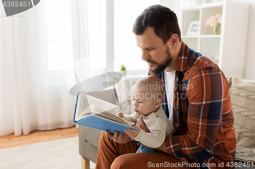 Image of happy father and little baby boy with book at home